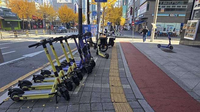 Electric scooters are neatly lined up at a designated parking zone for personal mobility devices in Dujeong-dong, Cheonan, South Chungcheong, on Nov. 11. The city has established 450 such parking zones across urban areas. [SHIN JIN-HO]