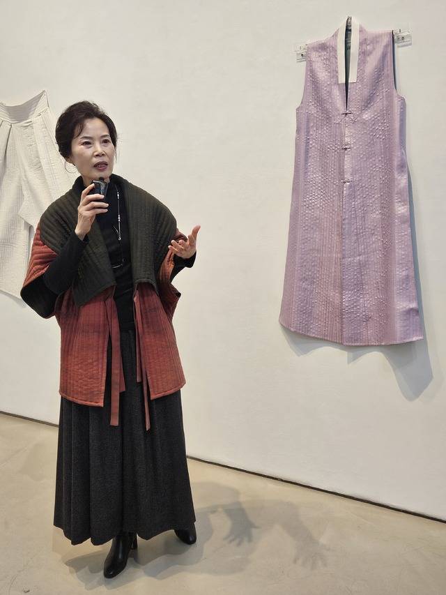 이순협 국가무형유산 누비장 우수 이수자가 17세기 심익상 묘에서 출토된 겹누비 배자 재현복식에 대해 설명하고 있다. 겉감(자미사)과 안감(문단)을 달리한 이 겹누비 배자는 출토복식 가운데 깃머리가 세모난 매부리형 남자 복식으로는 유일하다. 솜을 대지 않은 겹누비인데도 올록볼록한 반구슬 같은 요철이 표현되어 있다. 마법과 같은 아름다움을 한 땀 한 땀 바느질로 살려낸 누비옷의 우수함을 극적으로 드러내고 있다. 최미화 기자