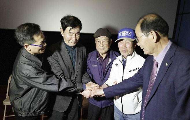 영화 ‘1980 사북’ 특별상영회가 열린 지난 4월 영월시네마에서 사북 항쟁동지회 명예회장 이원갑(왼쪽 둘째)씨가 사북사건 당시 진압에 투입된 전 영월경찰서 소속 경찰들과 손을 잡고 화해하고 있다. 영화사 느티 제공