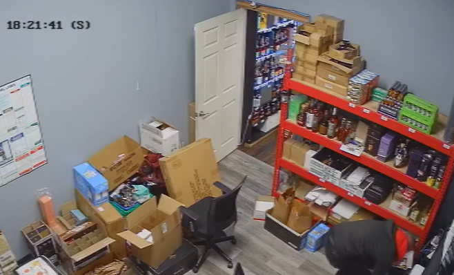 빨간색 후드티를 입은 한 남성이 주류 판매점 뒤편에 있는 사무실 내부를 뒤지고 있다. 유튜브 채널 ‘KPTV 폭스12’ 캡처