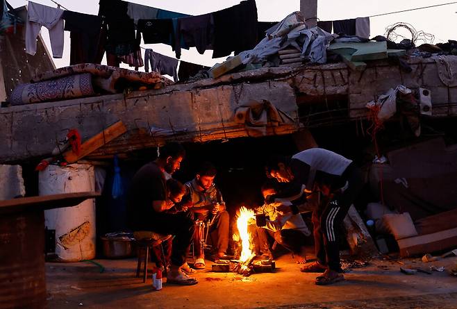 19일(현지시각) 가자지구 북부 지역에서 팔레스타인 주민들이 나무 장작으로 피운 모닥불 곁에 모여 추위를 피하고 있다. 가자지구에선 최근 내린 겨울 폭우에 팔레스타인 피난민들이 추위로 고통받고 있지만, 이스라엘은 가자지구 내로 연료 반입을 제한하고 있다. 로이터 연합뉴스