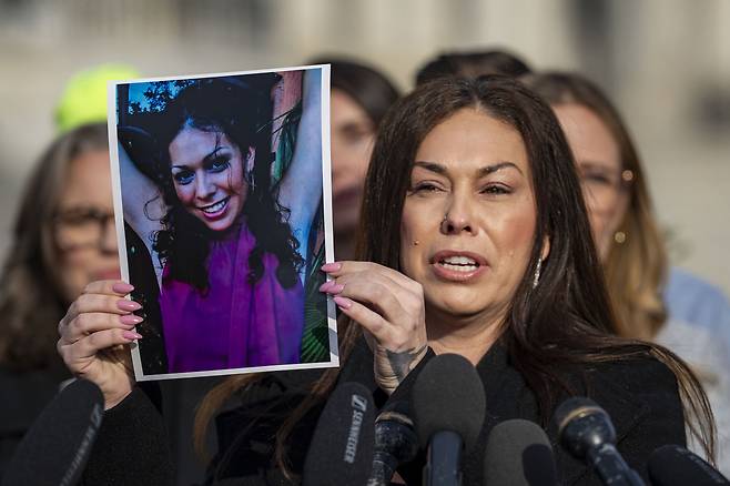 엡스타인 생존자인 헤일리 롭슨이 18일(현지시간) 미 의회 의사당 앞에서 자신의 어릴적 사진을 들어 보이며 “아이들을 위해 엡스타인 문건 공개에 투표해달라”고 호소하고 있다. UPI연합뉴스