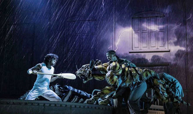 한국 초연을 앞둔 음악극 ‘라이프 오브 파이’의 해외공연의 스틸 장면으로, 대형 퍼펫으로 실감나게 제작된 호랑이와 주인공이 사투를 벌이고 있다. [에스앤코]