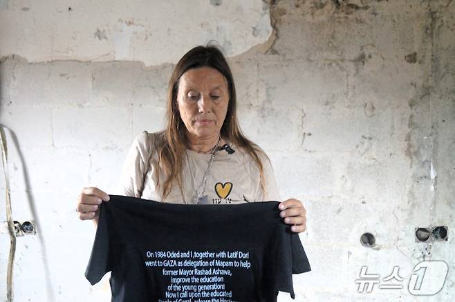 이스라엘 남부 키부츠 니르 오즈에서 주민인 리타 립시츠 씨가 지난 11일(현지시간) 한국 취재진에게 2023년 10월 7일 하마스가 벌인 만행을 상세히 설명했다. 들고 있는 셔츠엔 사망한 시아버지와 사연이 적혀 있다. 2025.11.11 ⓒ 최종일 기자=뉴스1