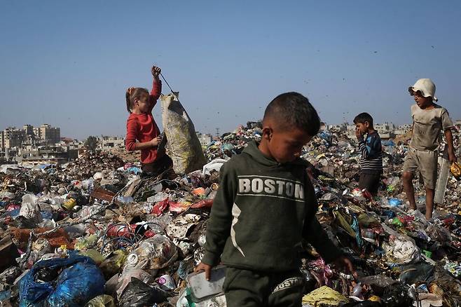 23일(현지시각) 팔레스타인 가자지구 중부 부레지 난민 캠프에 있는 쓰레기더미에서 팔레스타인 어린이들이 땔깜으로 사용할만한 쓰레기를 찾고 있다. AFP 연합뉴스