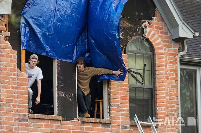 [텍사스주=AP/뉴시스] 24일(현지 시간) 미국 텍사스주 메모리얼 노스웨스트 지역에서 주민들이 토네이도로 인해 파손된 주택 창문에 방수포를 설치하고 있다. 2025.11.25.