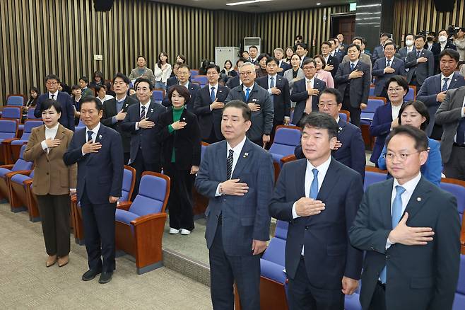 더불어민주당 정청래 대표, 김병기 원내대표를 비롯한 의원들이 27일 서울 여의도 국회에서 열린 의원총회에서 국기에 경례를 하고 있다. / 연합뉴스