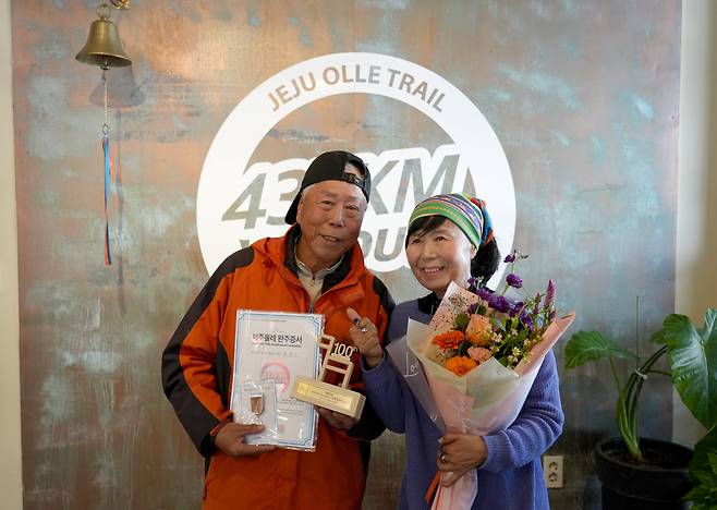제주올레 100회를 완주한 한창수씨가 100회 완주 기념증을 받고 서명숙 제주올레 이사장과 기념촬영을 하고 있다./(사)제주올레