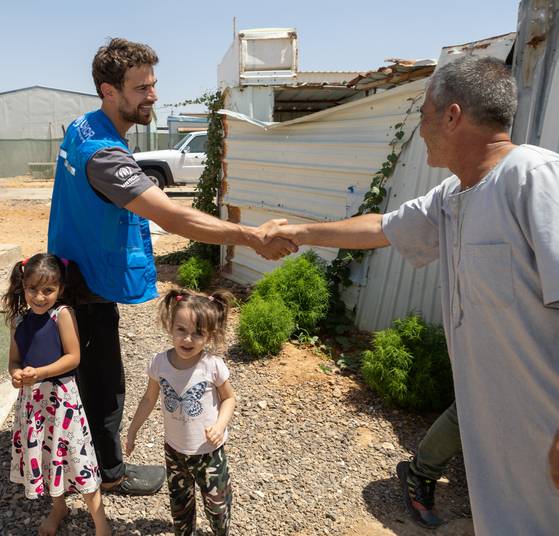 Actor Theo James, left, shakes hands with a Syrian man at the Azraq Refugee Camp in Jordan on July 25, 2023. James' grandfather fled Nazi-occupied Greece and found refuge in Damascus, Syria, during World War II. [UNITED NATIONS HIGH COMMISSIONER FOR REFUGEES]