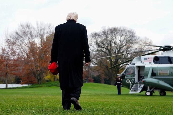 붉은색 야구모자를 손에 쥔 도널드 트럼프 미국 대통령이 2025년 11월22일 전용 헬기를 타기 위해 백악관 잔디밭을 지나고 있다. REUTERS 연합뉴스