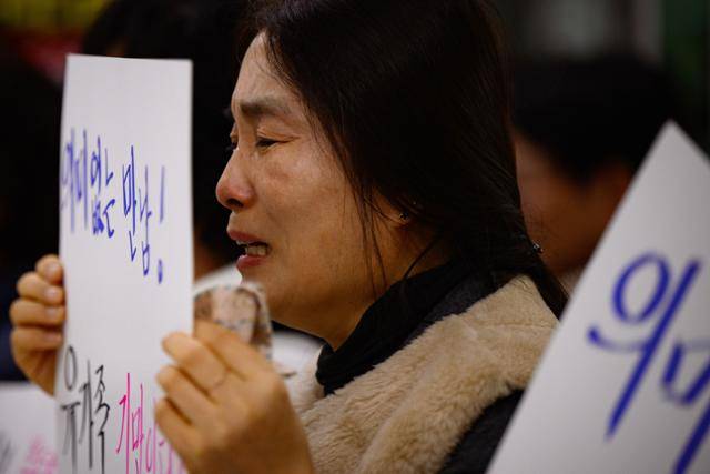 김윤덕 국토교통부 장관이 유가족과의 면담을 위해 무안공항을 찾은 26일 조미영씨가 김 장관 앞에서 '의미 없는 만남, 유가족 기만이다'라고 쓰인 피켓을 든 채 눈물을 흘리고 있다.