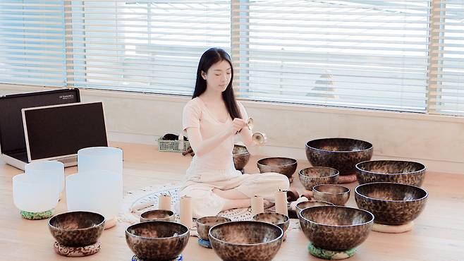 An instructor rubs singing bowls during a meditation session. [KANGWON LAND]