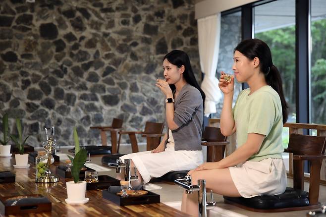 People drink tea while warming themselves with a footbath. [KANGWON LAND]