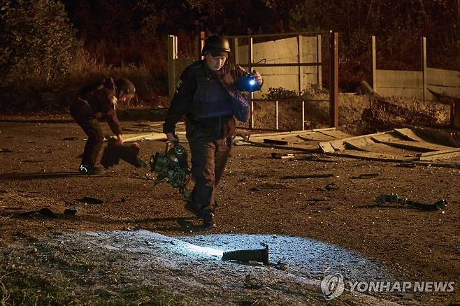 지난 10월 8일(현지시간) 러시아의 드론 공격을 받은 우크라이나 북부 하르키우에서 바닥에 떨어진 드론 파편을 옮기는 구조대원 [EPA 연합뉴스 자료사진. 재배포 및 DB 금지]