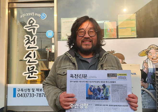 황민호 옥천신문 대표가 사무실 앞에서 신문을 들어 보이고 있다. 이재덕 기자