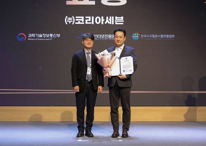 ‘2025 전자문서 산업인의 날’ 행사에서 문대우(좌측) 세븐일레븐 디지털혁신부문장이 부총리 겸 과학기술정보통신부장관 표창 수상 후 엄열 과학기술정보통신부 국장과 기념촬영을 하고 있다. 세븐일레븐 제공