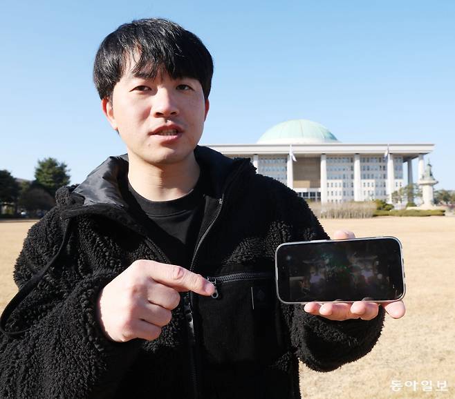 12·3 계엄 당시 임신한 아내를 뒤로 하고 “장갑차가 오면 차로라도 막겠다”며 국회로 향했던 최영신 씨(41)가 지난달 28일 국회 앞에서 당시 촬영한 사진을 보여주고 있다. 신 씨는 “계엄 직후 한동안 군 헬기가 쫓아오는 악몽에 시달렸다”면서도 “현장에서 부당한 명령에 따르지 않던 경찰과 군인을 목격하며 오히려 우리 사회에 대한 신뢰가 더 깊어졌다”고 했다. 신원건 기자 laputa@donga.com