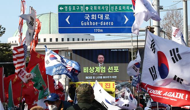 Pro-Yoon groups replay a video of Yoon's martial law decree during a demonstration in front of the National Assembly in Yeouido, Seoul, commemorating the declaration's first anniversary on Wednesday. (Yonhap)