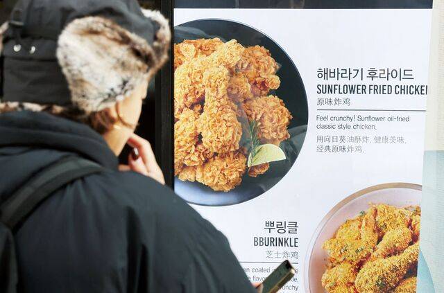 서울시내 한 치킨집 앞에서 2일 한 시민이 치킨 메뉴판을 바라보고 있다. 정부는 오는 15일부터 10대 주요 치킨 프랜차이즈 메뉴판에 조리 전 중량을 표시하는 ‘중량 표시제’를 도입한다고 이날 밝혔다. 가격은 그대로 두고 양을 줄이는 ‘슈링크플레이션’ 꼼수를 방지하기 위해서다. 연합뉴스