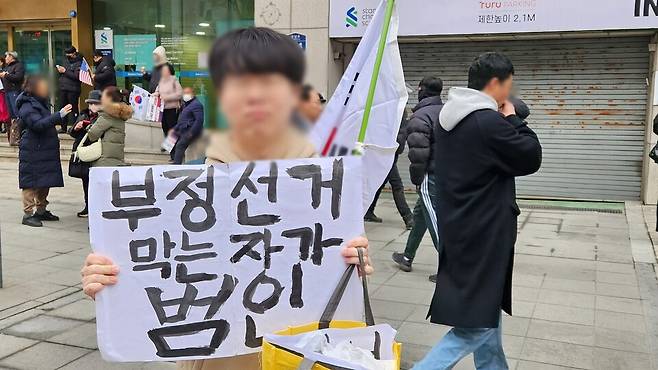 2월15일 오전 광주 동구 금남로 윤석열 당시 대통령 탄핵 반대집회 행사장에 경기도 부천에서 왔다는 한 청년이 '부정선거 막는 자가 범인이다'는 손팻말을 들고 사진촬영에 응하고 있다. ⓒ시사저널 정성환