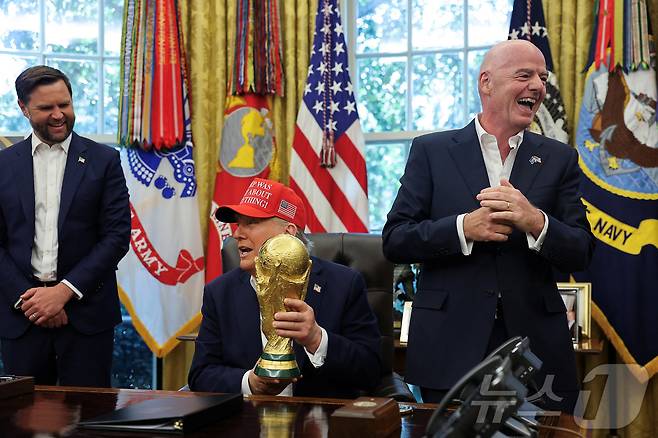 도널드 트럼프 미국 대통령이 8월 22일(현지시간) 워싱턴DC 백악관 집무실에서 '트럼프가 전부 옳았다!'(Trump Was Right About Everything!)라고 적힌 모자를 쓴 채 FIFA 월드컵 트로피를 들고 2026년 FIFA 월드컵 관련 발표를 하고 있다. 2025.08.22. ⓒ 로이터=뉴스1 ⓒ News1 윤다정 기자