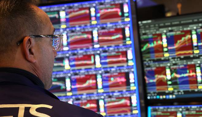 A trader works at his desk on the floor of the New York Stock Exchange (NYSE) after the opening bell in New York on Dec. 3. Wall Street's main stock indices dipped on Wednesday after data showed US businesses unexpectedly shed jobs last month. [AFP/YONHAP]
