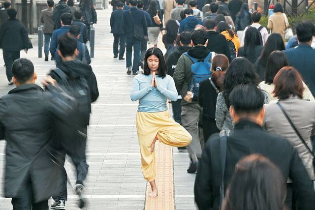 박혜영 씨가 출근하는 직장인들 사이에서 나무자세 요가를 하며 명상하고 있다.