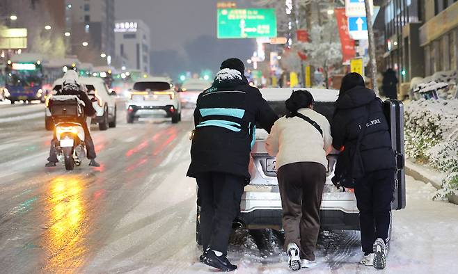4일 서울 마포구 홍대 인근에서 제설작업이 완료되지 못한 도로에서 시민들이 언덕길 차를 밀고 있다. 연합뉴스