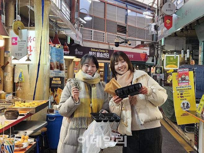 히요시 미나미(25)씨와 문수빈(25)씨가 지난 4일 통인시장에서 음식을 기다리며 도시락을 들고 있다. (사진=방보경 기자)