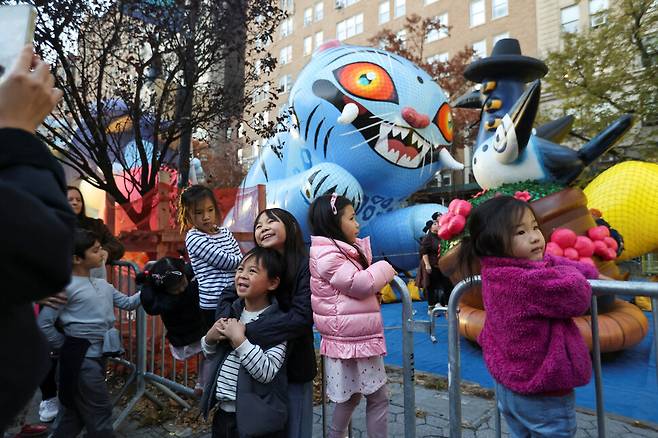 미국 추수감사절 연휴를 하루 앞둔 지난달 26일 뉴욕 맨해튼에서 열린 메이시스 추수감사절 퍼레이드 중 아이들이 뮤지컬 애니메이션 ‘케이팝 데몬 헌터스’에 나오는 호랑이 더피와 까치 풍선 앞에서 사진을 찍고 있다. 로이터 연합뉴스