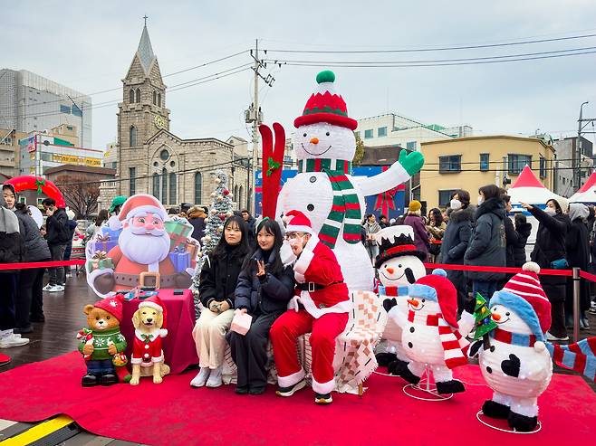 Two women pose for a photograph with a man dressed in a Santa Claus outfit at the European Market in Seongbuk District, central Seoul, on Dec. 7. [MICHAEL LEE]