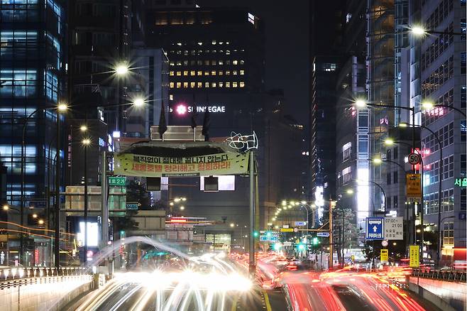 정리해고 철회를 촉구하며 고공 농성 중인 세종호텔 해고 노동자 고진수씨가 지난달 11월 23일 밤 서울 중구 세종호텔 앞 교통시설 구조물 위에서 손전등을 이용해 ‘승리’를 쓰고 있다. 사진은 조리개 f20에 20초 장노출로 찍었다. 백소아 기자 thanks@hani.co.kr