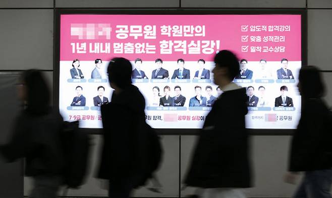 공무원 시험 수험생들이 서울 노량진역에 위치한 공무원 학원 광고판 앞을 지나가고 있다. 연합뉴스