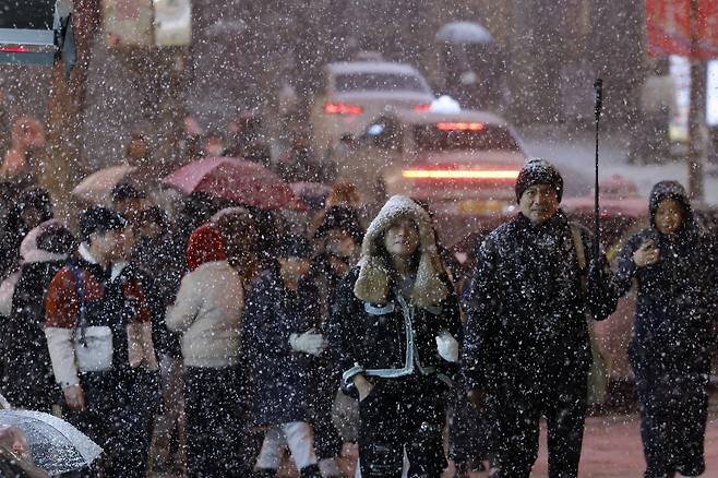 Tourists enjoy falling snow in central Seoul on Dec. 4. [NEWS1]