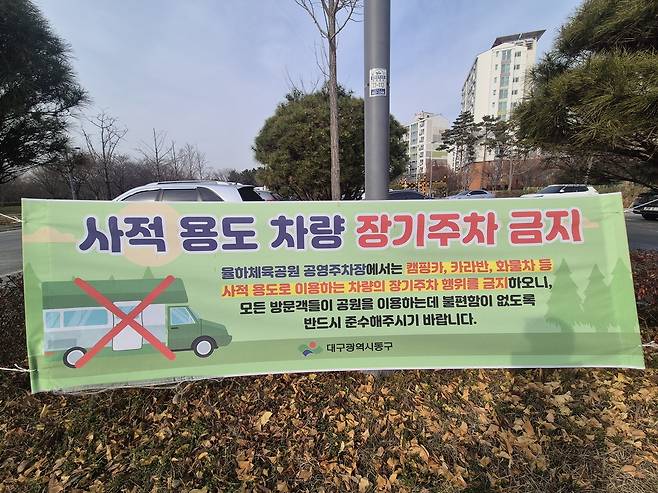 '계도 현수막은 있지만'  (대구=연합뉴스) 박세진 기자 = 10일 대구 동구 율하체육공원 무료 공영주차장에 장기 주차 금지를 알리는 동구청 현수막이 설치돼 있다. 2025.12.10 psjpsj@yna.co.kr