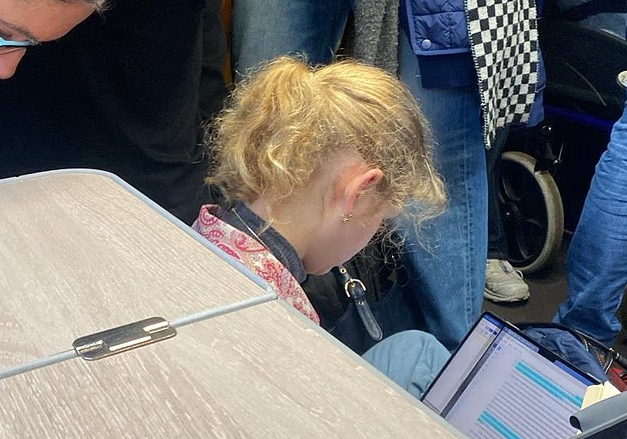 영국 왕위 계승 서열 17위인 레이디 루이즈 윈저가 열차 객실 바닥에서 다리를 꼬고 앉아 에세이를 쓰고 있다. [데일리메일 캡처]