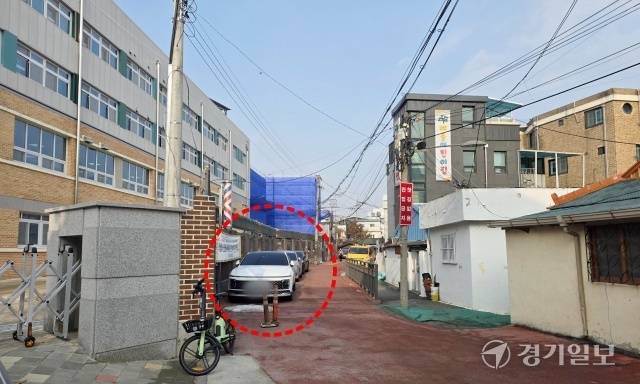 광주시 경안동 광주초등학교 후문 앞 막다른 통학로. 븕은색 포장도로 학교담장 옆으로 차량 여러대가 주차돼 있다. 이 도로는 어린이보호구역으로 지정되지 않아 사고 위험이 크지만 시와 학교 측은 책임공방을 벌이고 있어 대책 마련이 시급하다. 한상훈기자