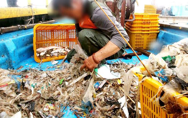 ▲&nbsp;2021년 한강하구 어민들이 새우잡이 조업을 하고 있다. 그물에 새우보다 쓰레기가 많이 걸려 있는 걸 확인한 어민이 허탈해하고 있다. /인천일보DB