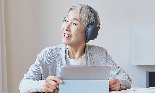 헤드폰을 착용한 채 태블릿으로 공부하고 있는 고령 여성의 모습. 게티이미지뱅크