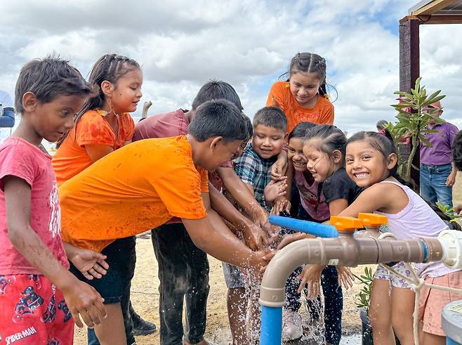 브라질 아마존 원주민 어린이들이 국제위러브유가 설치한 물펌프에서 나오는 깨끗한 물로 손을 씻으며 기뻐하고 있다.