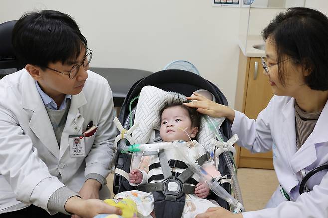 Eight-month-old Park Seo-rin, who was born with an exposed heart, is surrounded by doctors who performed the procedures at Seoul Asan Medical Center [SEOUL ASAN MEDICAL CENTER]