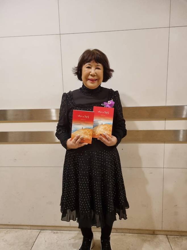 자신의 다섯 번째 시집 ‘머무르고 싶은 순간들’을 들어보이며 포즈를 취하고 있는 김경희 시인. 우진선박 제공