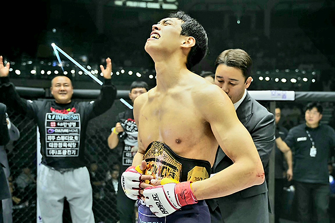 윤태영이 2025년 12월 서울특별시 중구 장충체육관에서 초대 로드FC 웰터급 타이틀 획득 후 기뻐하고 있다. 챔피언 벨트를 채워주는 대한MMA총협회 정문홍 회장. 사진=세계격투스포츠협회
