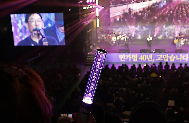 한 참석자가 ‘깨어 있는 시민의 조직된 힘’이라고 적힌 응원봉을 들고 공연을 보고 있다.