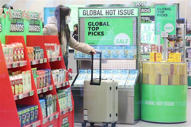 A foreign visitor browses cosmetics along a street in Seoul’s Myeongdong area on Dec. 21.  Korea’s cosmetics e-commerce export volume jumped to $350 million in 2023 from $50 million in 2019, marking a compound annual growth rate of 62.7 percent, according to data from Korea Health Industry Development Institute on Sunday. [YONHAP]