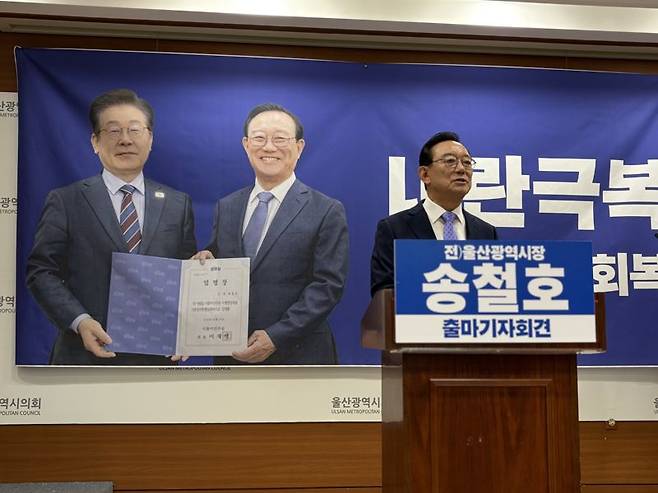 송철호 전 울산시장이 22일 내년 울산시장 선거 출마를 선언하면서 이재명 대통령과 함께 찍은 사진을 회견장 배경 현수막으로 준비했다. 이 대통령과의 친분을 강조한 것으로 보인다. 울산시의회 제공