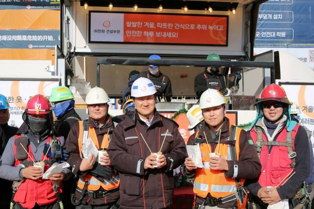 한화 건설부문이 겨울철 한파 속 현장 직원들을 격려하기 위해 운영하는 ‘겨울간식차’ 앞에서 직원들이 간식을 들고 웃고 있다. 사진 제공=한화 건설부문