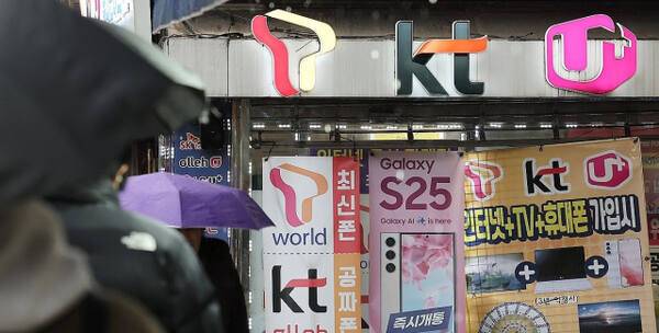 휴대전화를 개통할 때 신분증만 제시하던 것에서 패스 앱을 이용해 얼굴 사진을 찍어 본인임을 확인받는 절차가 시범 실시되는 23일 서울의 한 휴대폰 매장 앞을 시민들이 오가고 있다. 연합뉴스