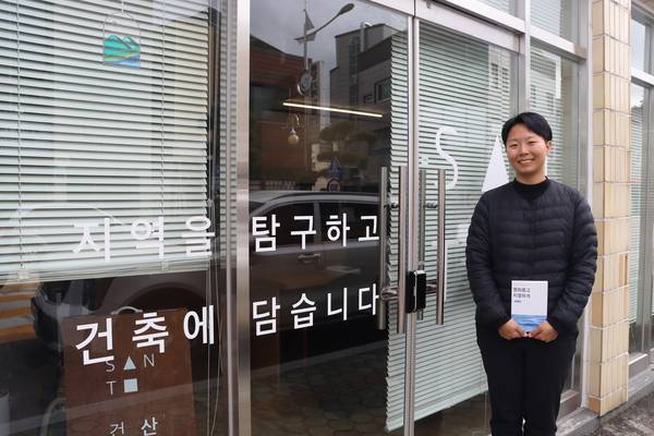 문주원 산토건축 대표가 남해군 서면 자신의 사무실 앞에서 그가 쓴 책 를 들고 사진을 찍고 있다. /주성희 기자