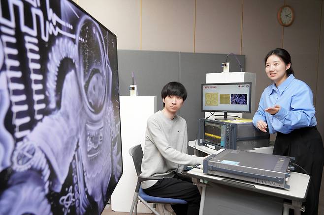 연구원들이 액자 형태의 분산형 RIS에 전파를 발사하고 통신 품질을 측정하는 모습. /LG유플러스